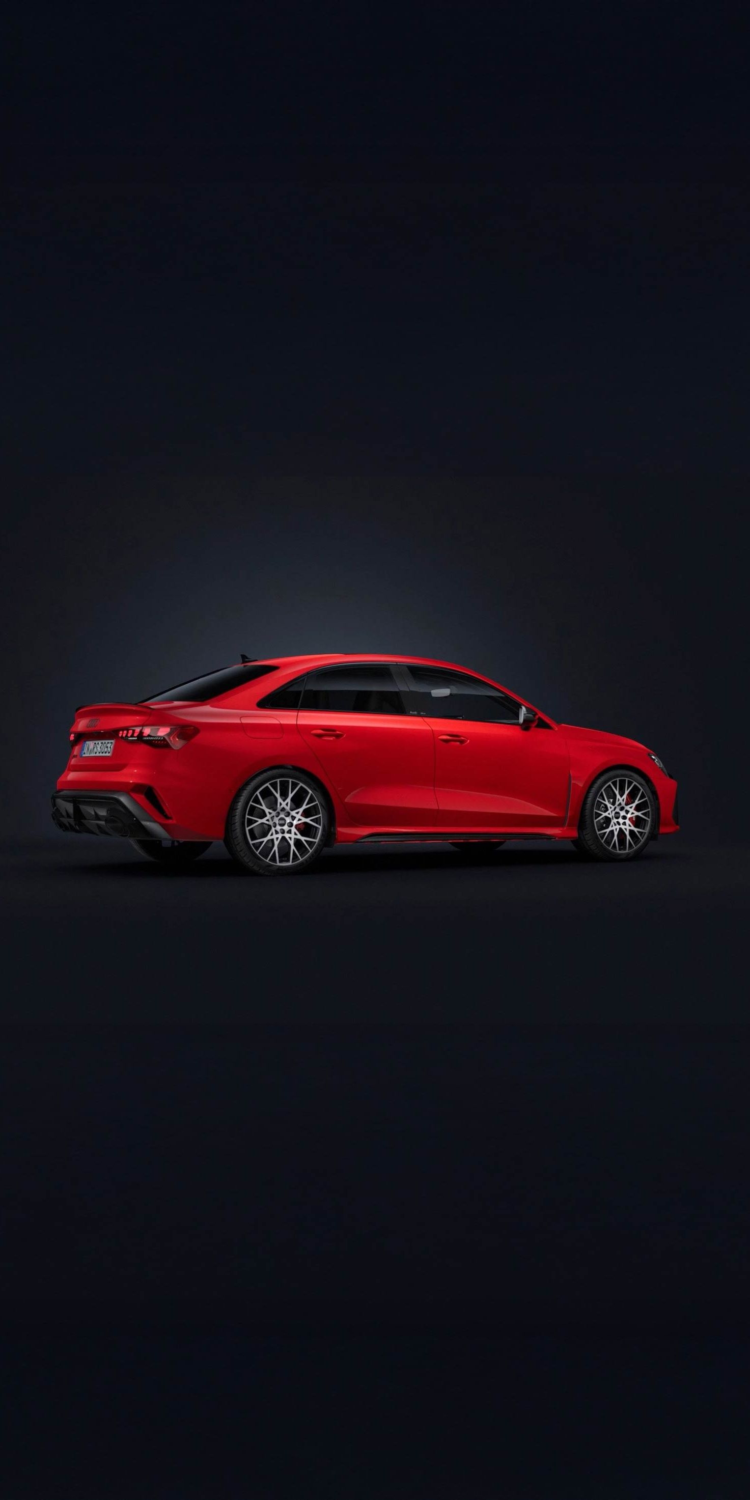 Die Audi RS 3 Limousine steht auf dunklem Hintergrund und dreht sich leicht auf die rechte Seite.