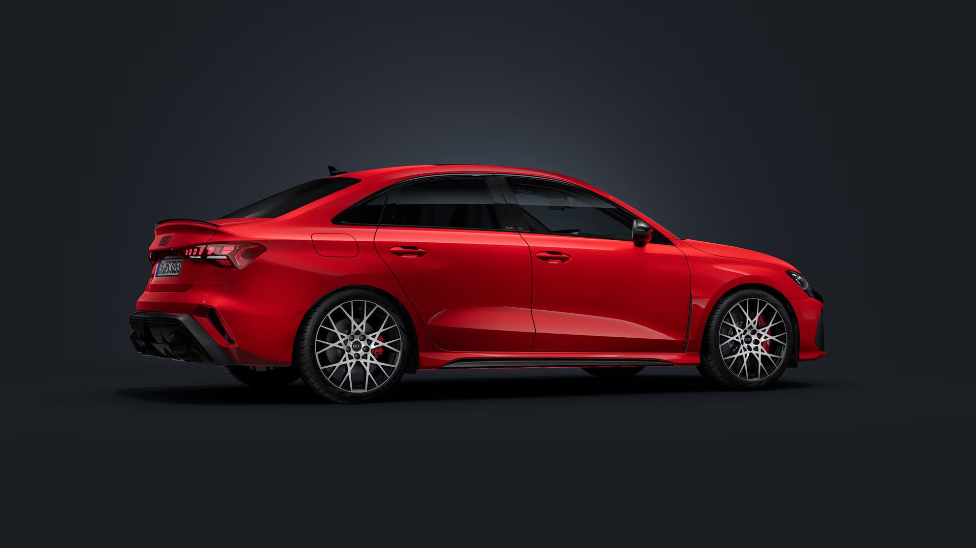 Die Audi RS 3 Limousine steht auf dunklem Hintergrund und dreht sich leicht auf die rechte Seite.