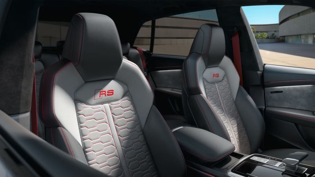 Blick auf die Sportsitze mit Lederausstattung Valcona Audi exclusive in Jetgrau/Silber mit Kontrastnähten, Gurten und gesticktem RS-Emblem auf den Lehnen und auf den Fußmatten in Karmesinrot.