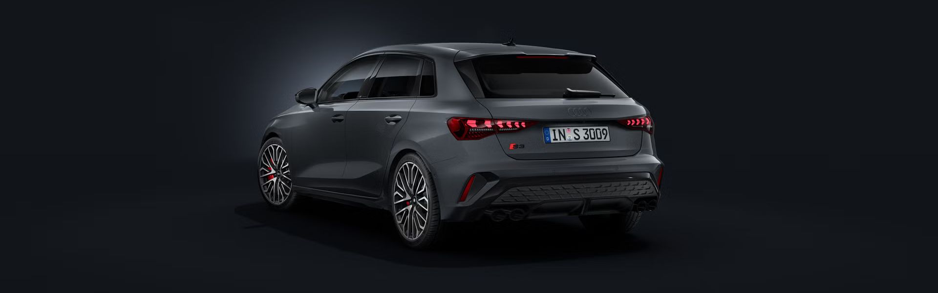 Der Audi S3 Sportback schräg von hinten auf dunklem Hintergrund.