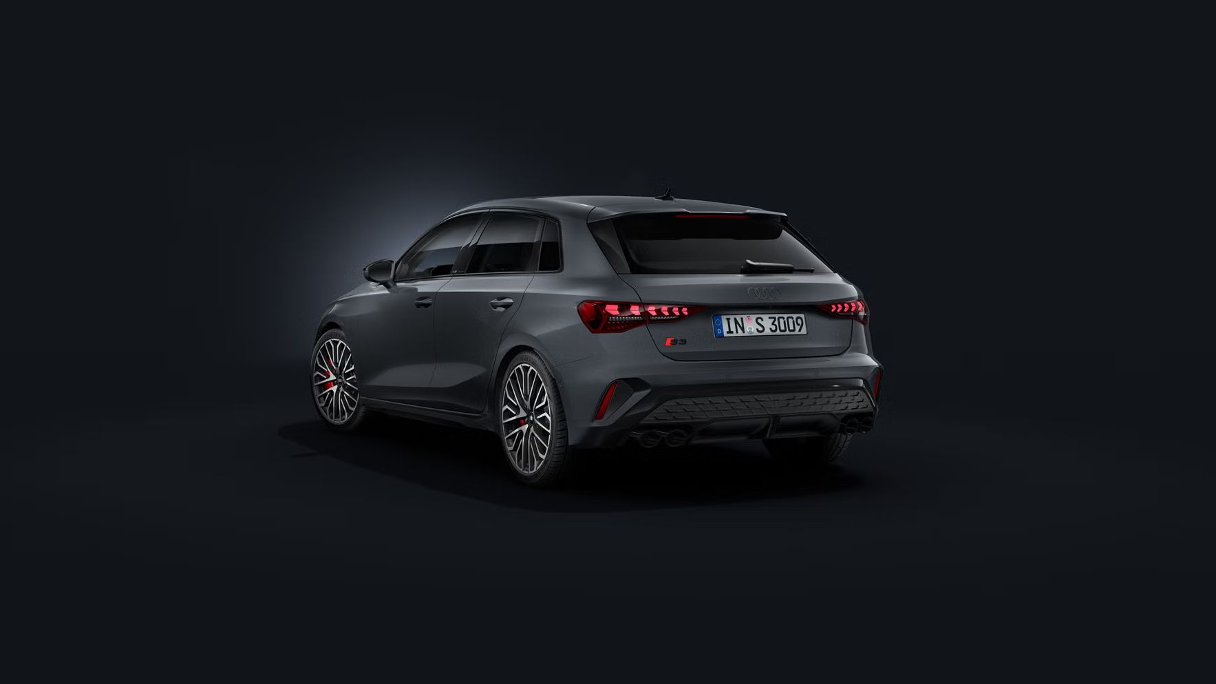 Der Audi S3 Sportback schräg von hinten auf dunklem Hintergrund.