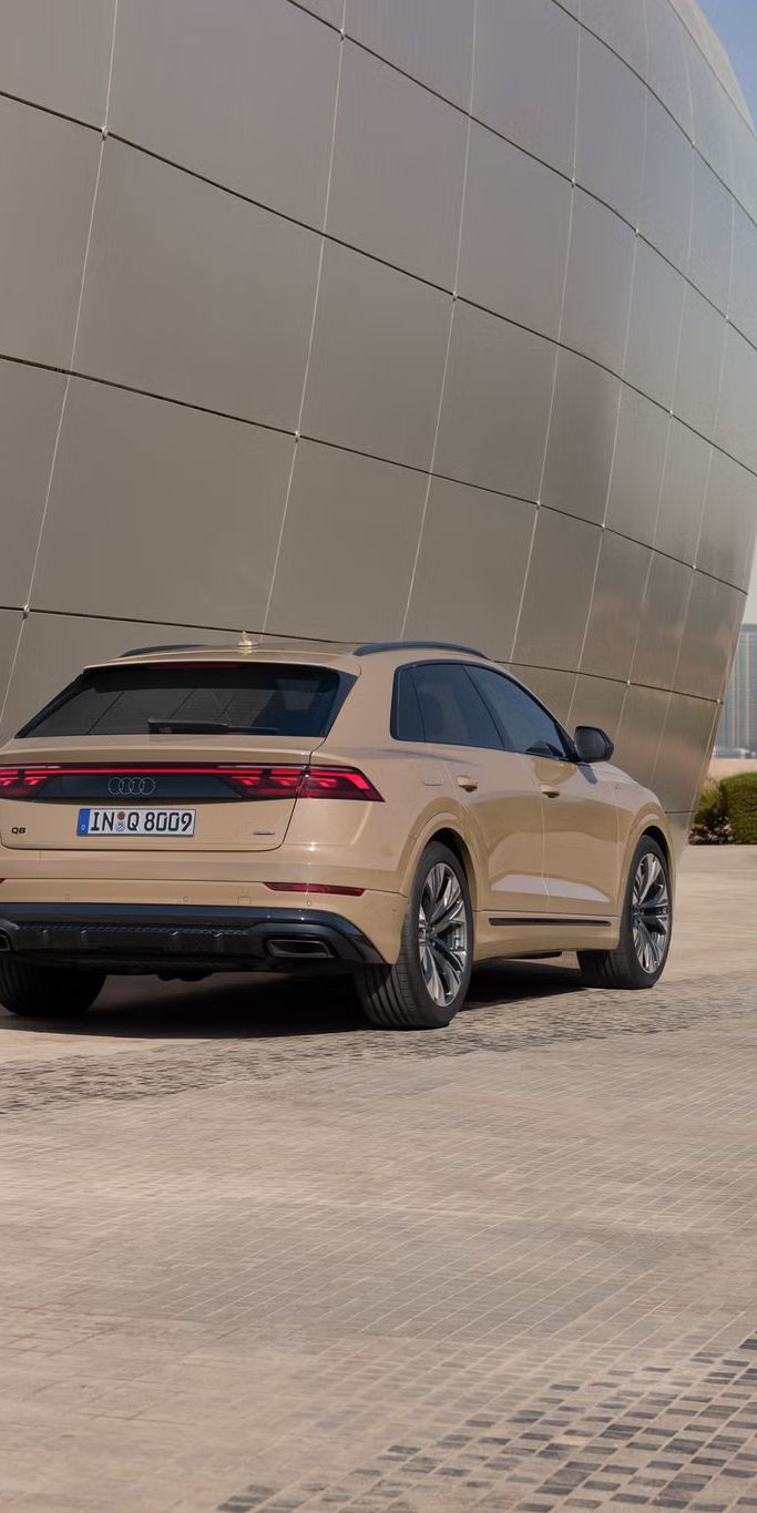 Der Q8 SUV schräg von hinten parkt vor einem modernen Gebäude. Nahaufnahme des Hecks.