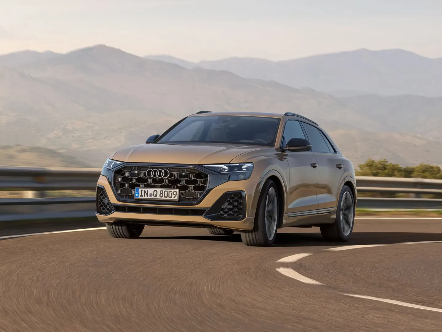 Der Audi Q8 SUV passiert eine Kurve, im Hintergrund eine bergige Landschaft bei wolkenlosem Himmel.