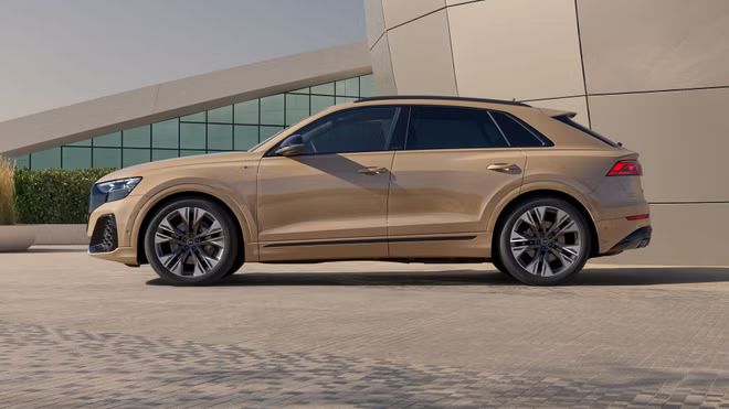 Der Audi Q8 SUV von der Seite, parkend vor einem futuristischem Gebäude.