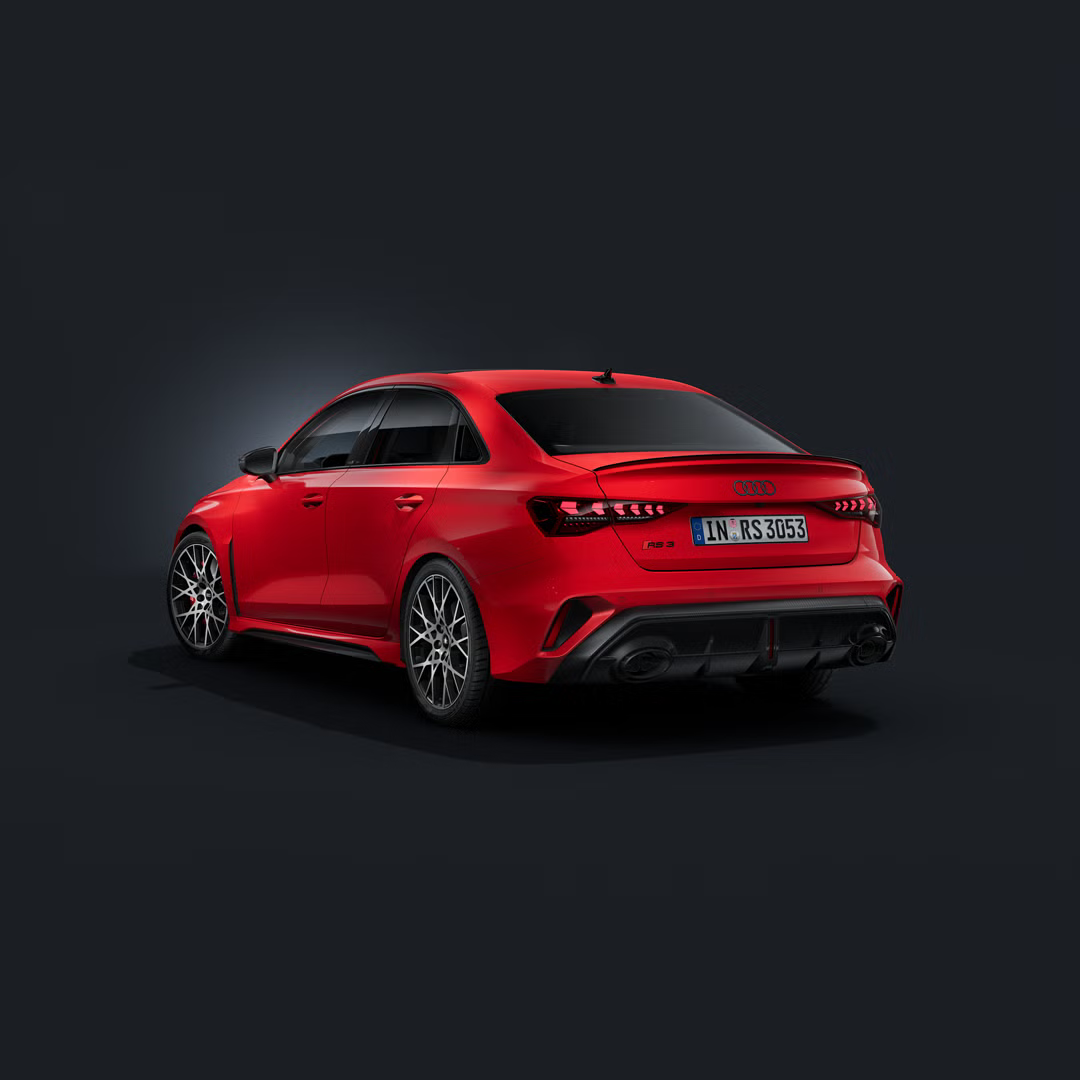 Die Audi RS 3 Limousine schräg von hinten auf dunklem Hintergrund.