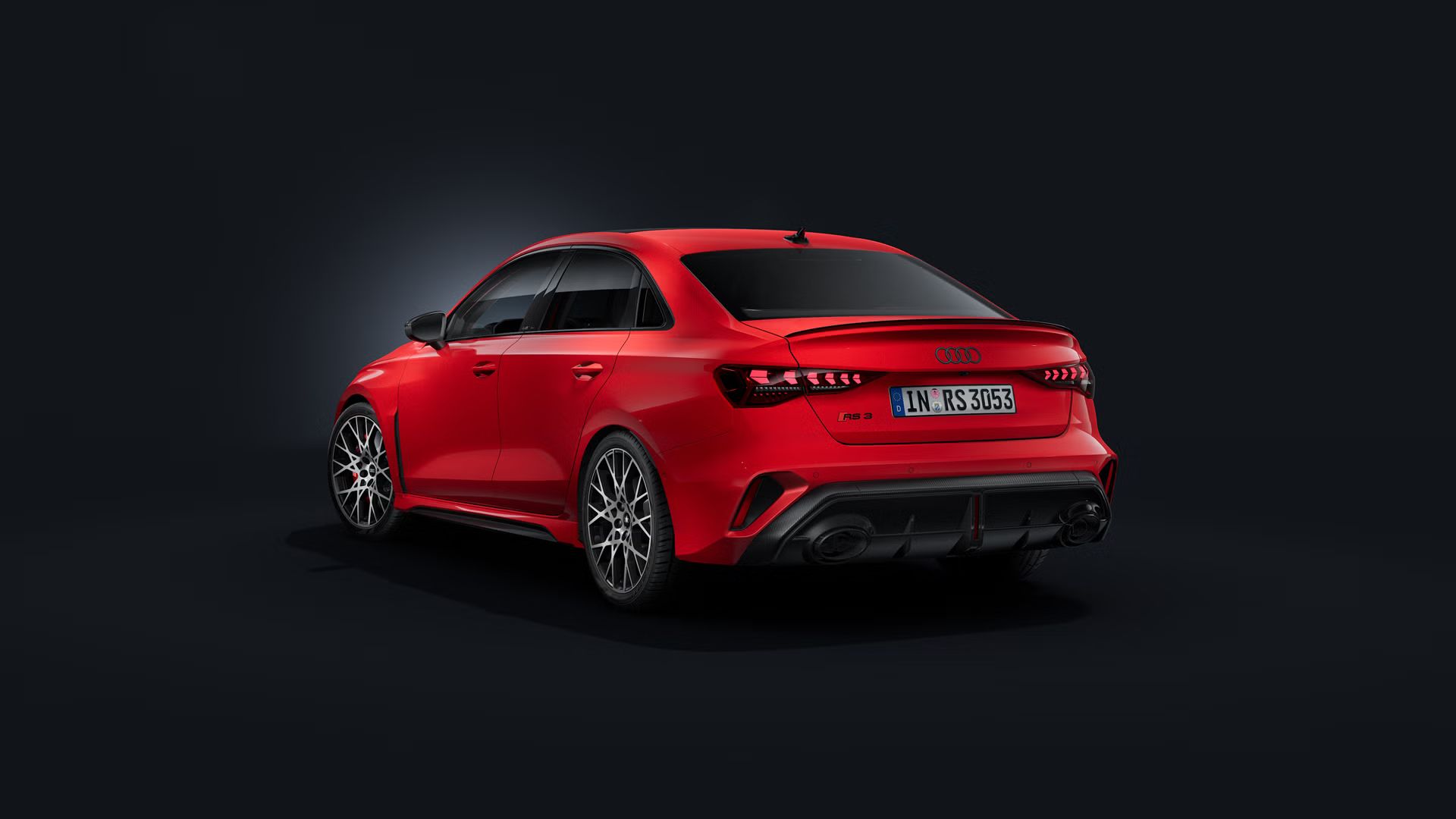Die Audi RS 3 Limousine schräg von hinten auf dunklem Hintergrund.
