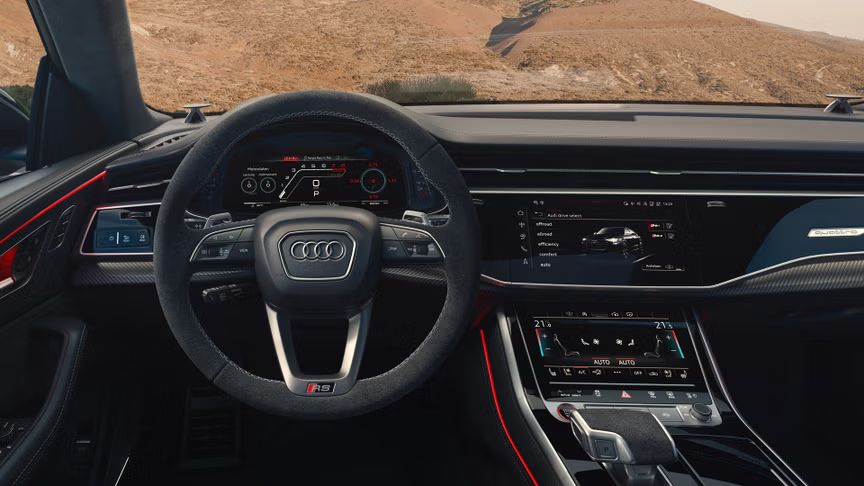 Blick von hinten auf das Cockpit des RS Q8 SUV mit Fokus auf das Lenkrad und die digitalen Displays. Durch die Windschutzscheibe sind karge Felsen zu erkennen.
