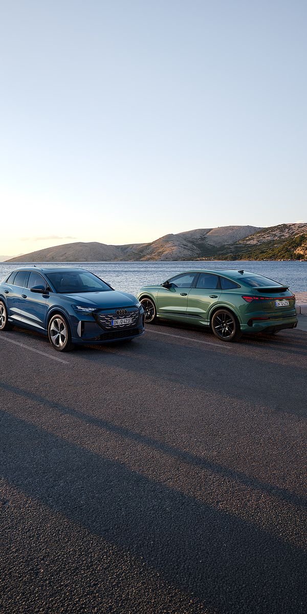 Q4 SUV e-tron quattro performance și Q4 Sportback e-tron quattro performance parcate pe un drum de coastă, cu marea și munții în fundal.