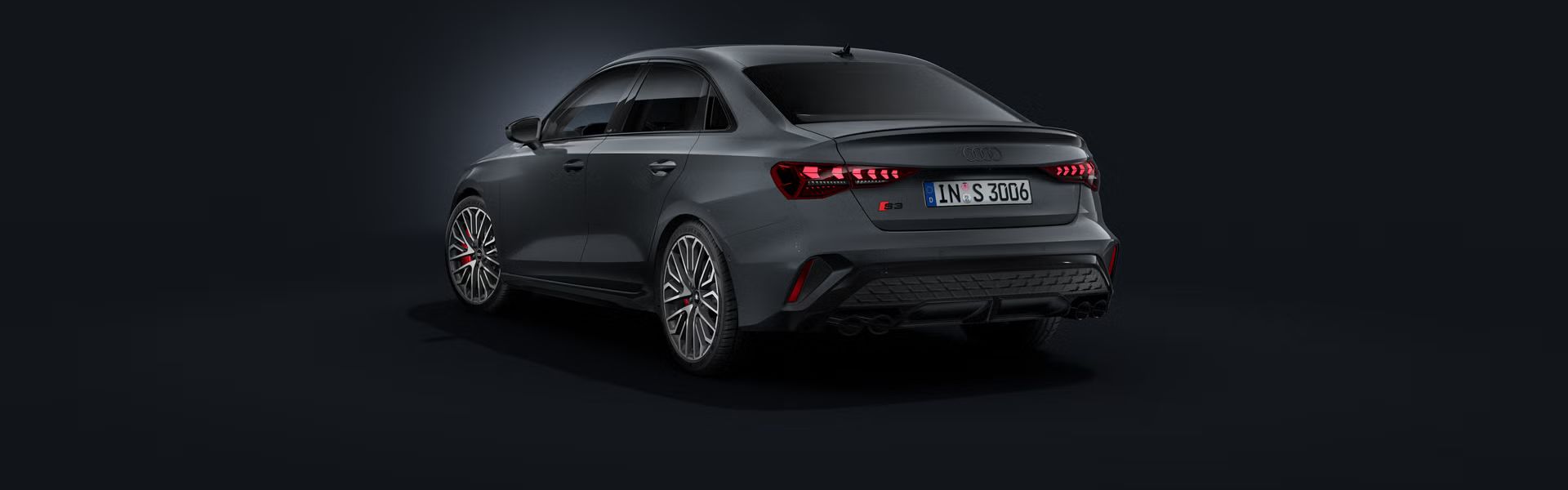 Die Audi S3 Limousine schräg von hinten auf dunklem Hintergrund.