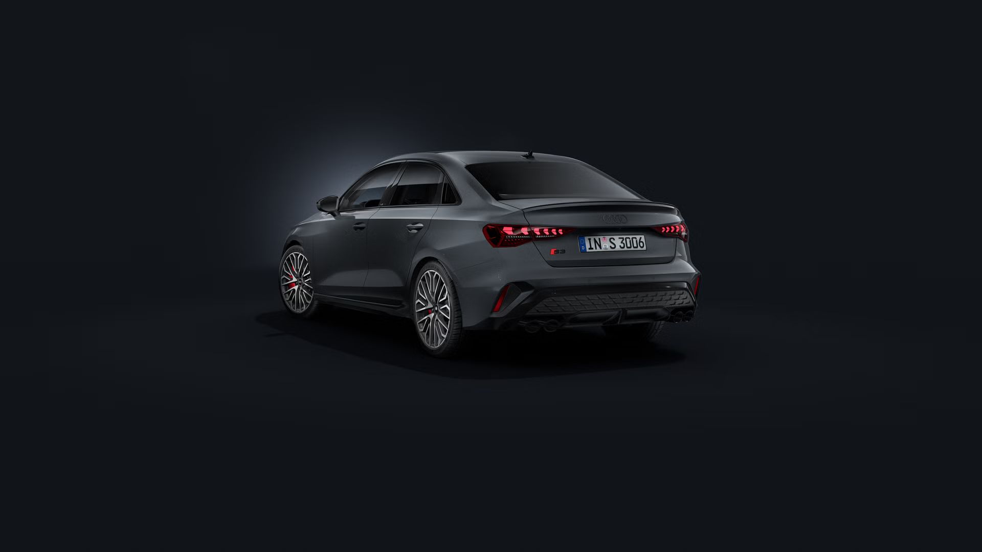 Die Audi S3 Limousine schräg von hinten auf dunklem Hintergrund.