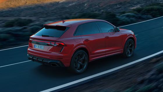 Der RS Q8 SUV performance von schräg hinten auf einer Bergstraße. Die Sonne beleuchtet die felsige Landschaft im Hintergrund, das Fahrzeug im Schatten.