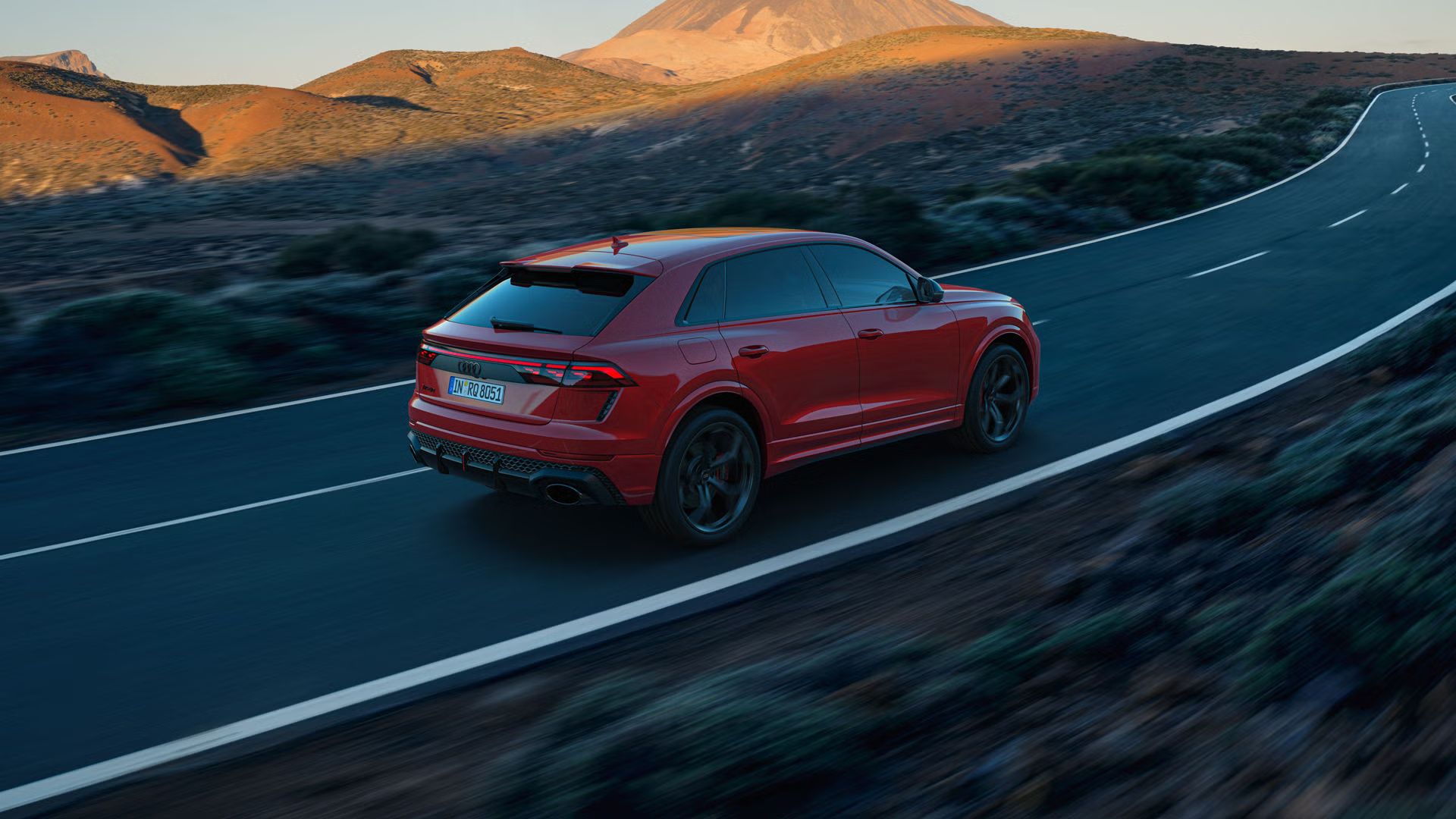 Der RS Q8 SUV performance von schräg hinten auf einer Bergstraße. Die Sonne beleuchtet die felsige Landschaft im Hintergrund, das Fahrzeug im Schatten.