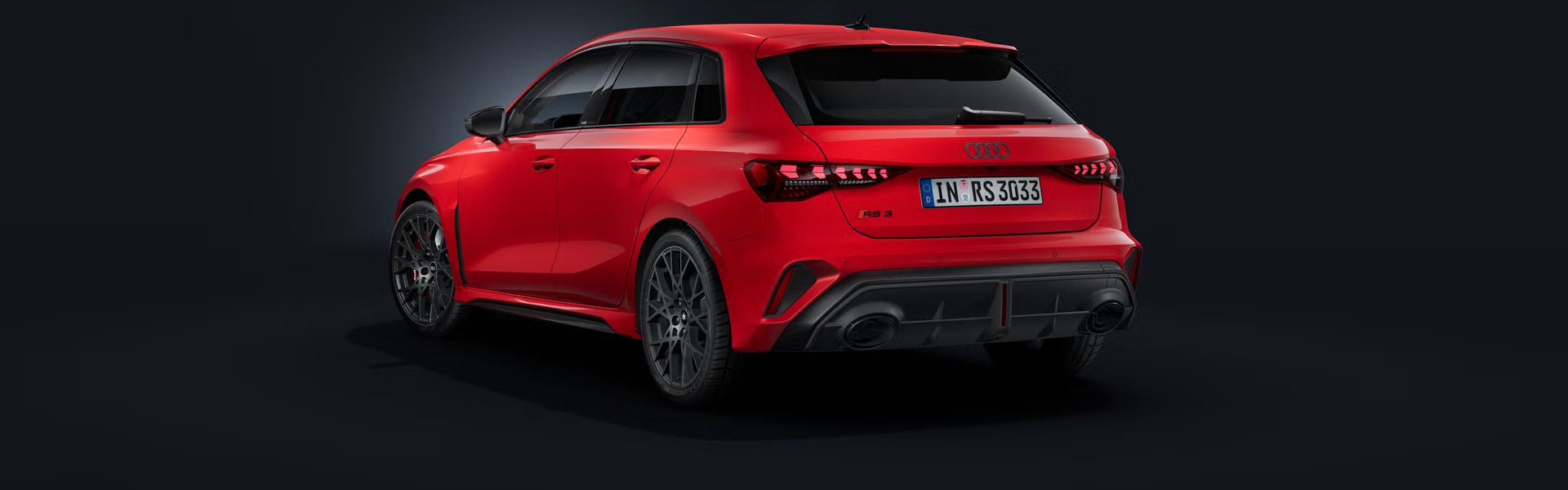 Der Audi RS 3 Sportback schräg von hinten auf dunklem Hintergrund.