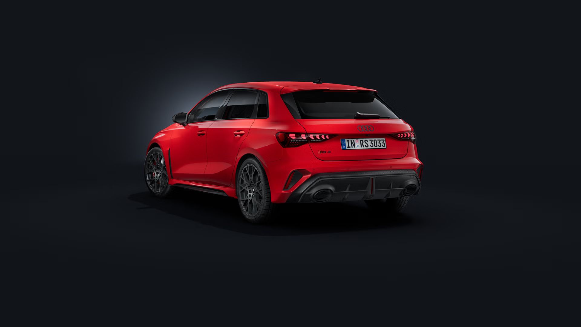 Der Audi RS 3 Sportback schräg von hinten auf dunklem Hintergrund.