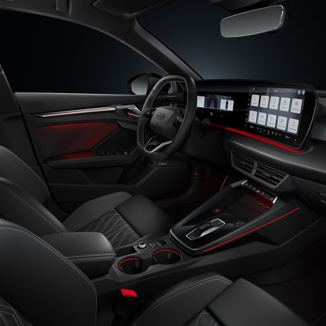 Blick von der Beifahrerseite auf das Cockpit mit Sportlenkrad, beleuchteter Mittelkonsole und Ambiente-Licht.