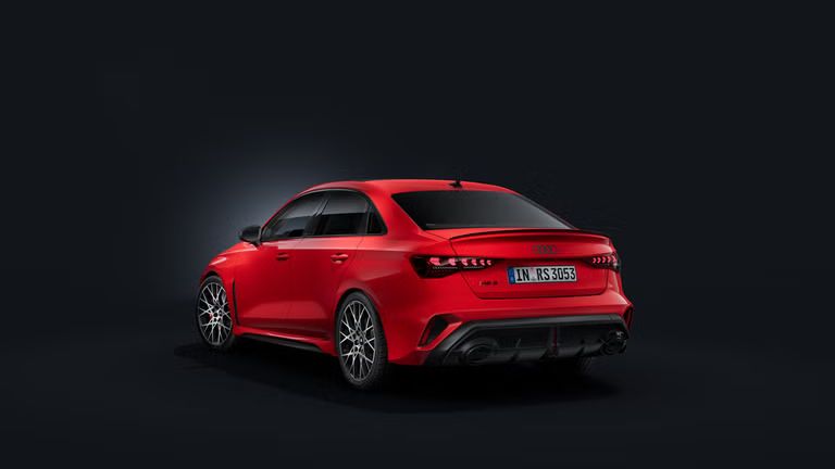 Die Audi RS 3 Limousine schräg von hinten auf dunklem Hintergrund.