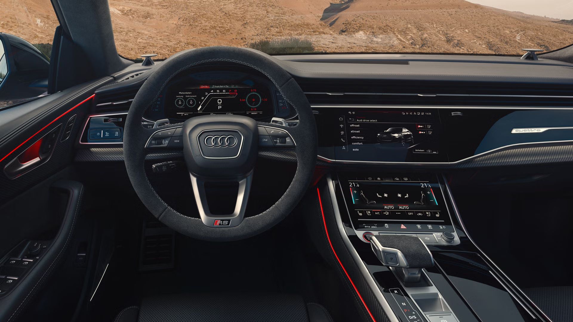 Blick von hinten auf das Cockpit des RS Q8 SUV mit Fokus auf das Lenkrad und die digitalen Displays. Durch die Windschutzscheibe sind karge Felsen zu erkennen.